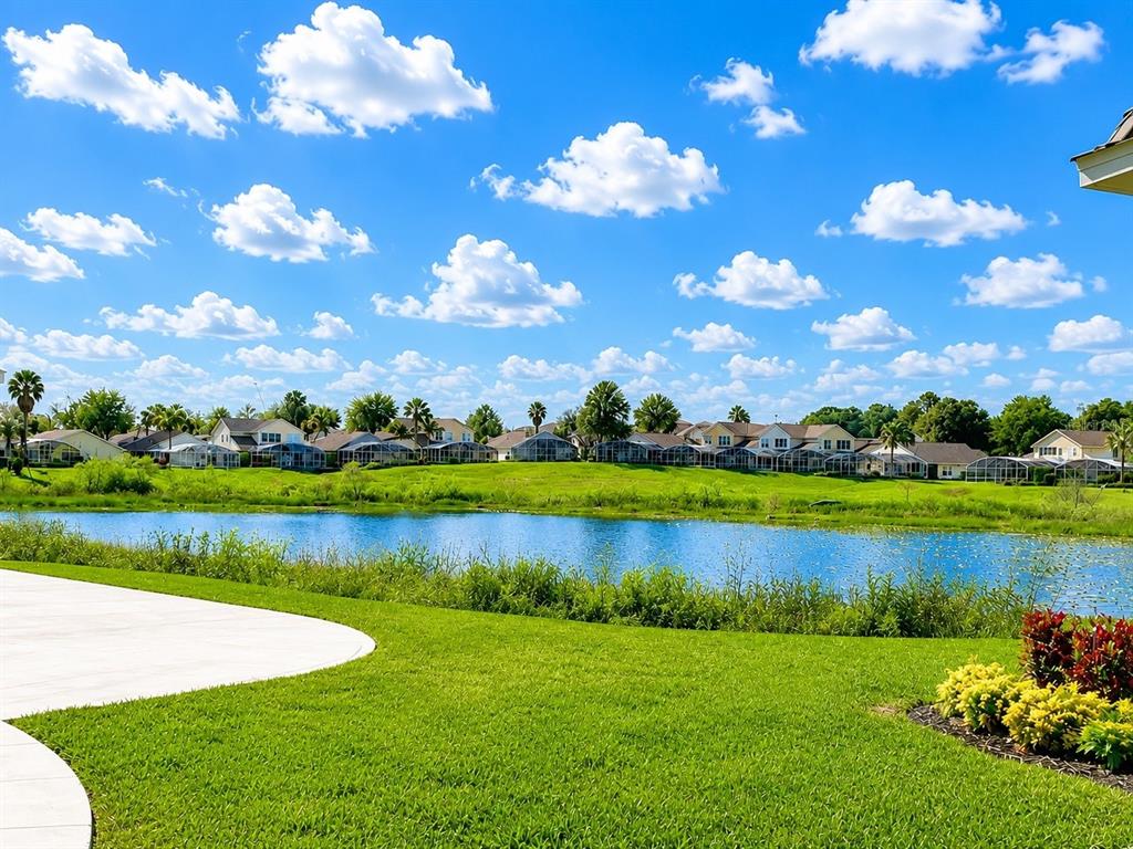 A view of a backyard lawn, a pond, and a row of houses under a sky — 290 ABERDEEN STREET, DAVENPORT, FL