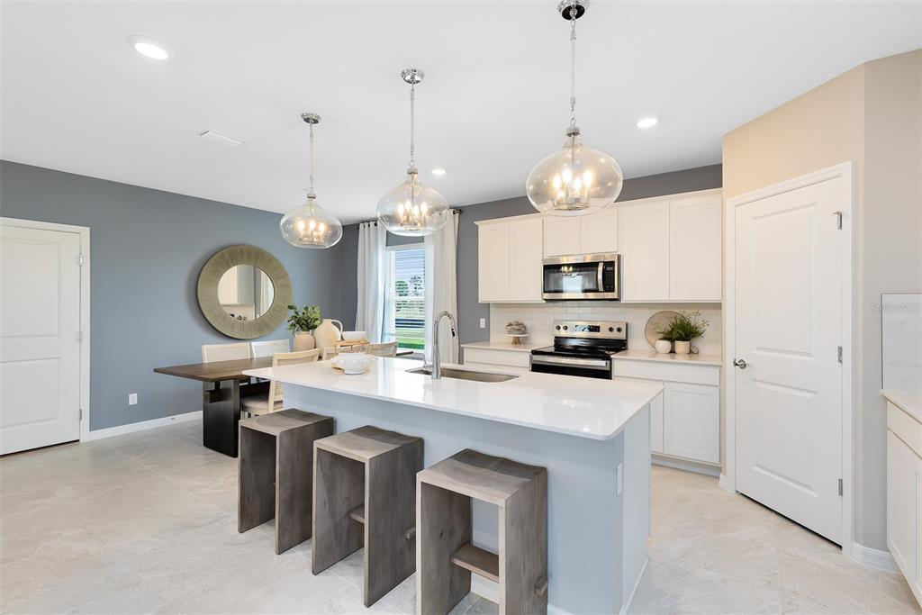 A kitchen with white cabinets, a quartz island, and a dining area with gray walls — 4713 ORANGE FLORA ALLEY, CLERMONT, FL