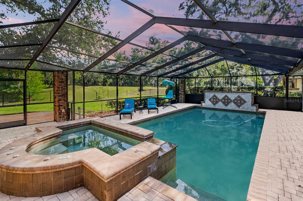 A screened-in pool and hot tub area with brick pavers overlooking a grassy yard — 2778 ST ANDREWS BOULEVARD, TARPON SPRINGS, FL