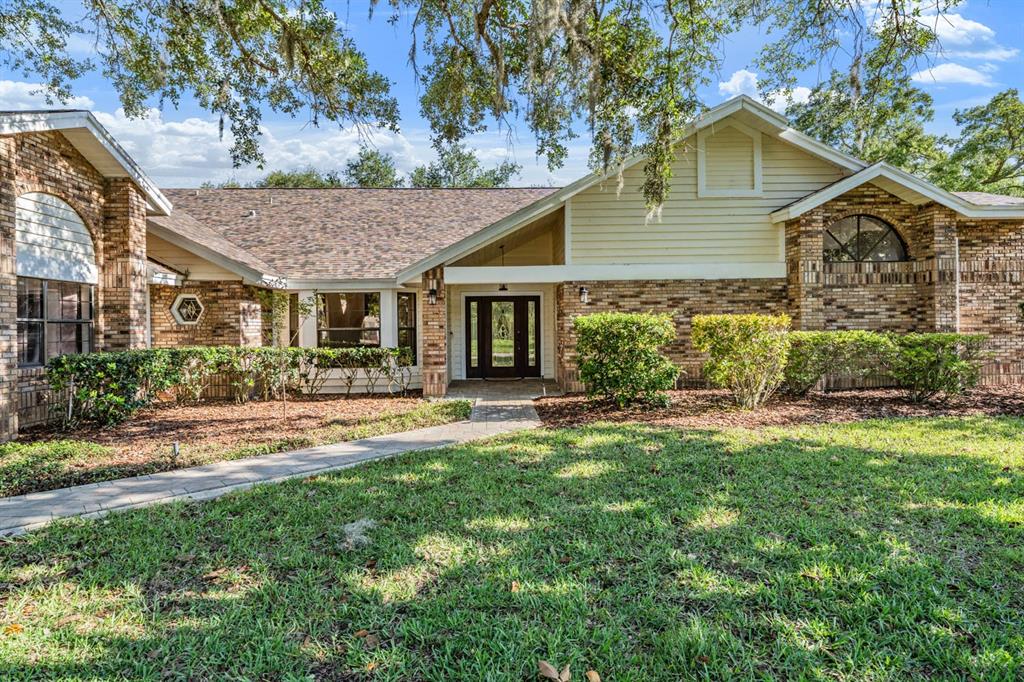 A single-story brick and siding house with a paved walkway leading to the front entrance — 2778 ST ANDREWS BOULEVARD, TARPON SPRINGS, FL