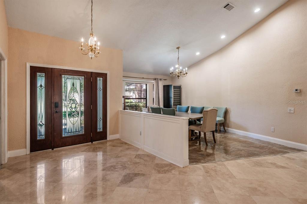 A foyer with tile floors leads to a dining area featuring a half-wall and chandeliers — 2778 ST ANDREWS BOULEVARD, TARPON SPRINGS, FL
