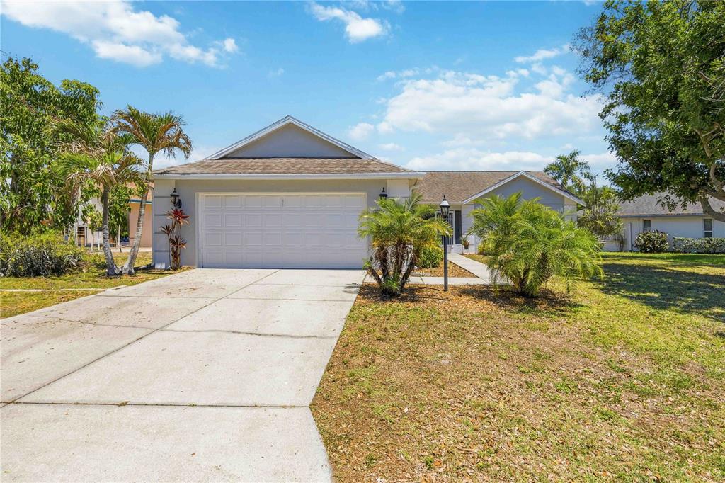 A single-story house with a two-car garage, a concrete driveway, and palm trees — 4851 HAMLETS GROVE DRIVE, SARASOTA, FL