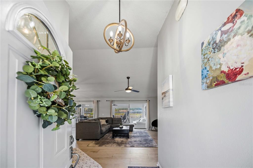 An entryway leads into a living room with vaulted ceilings, a chandelier, and wood flooring — 4851 HAMLETS GROVE DRIVE, SARASOTA, FL