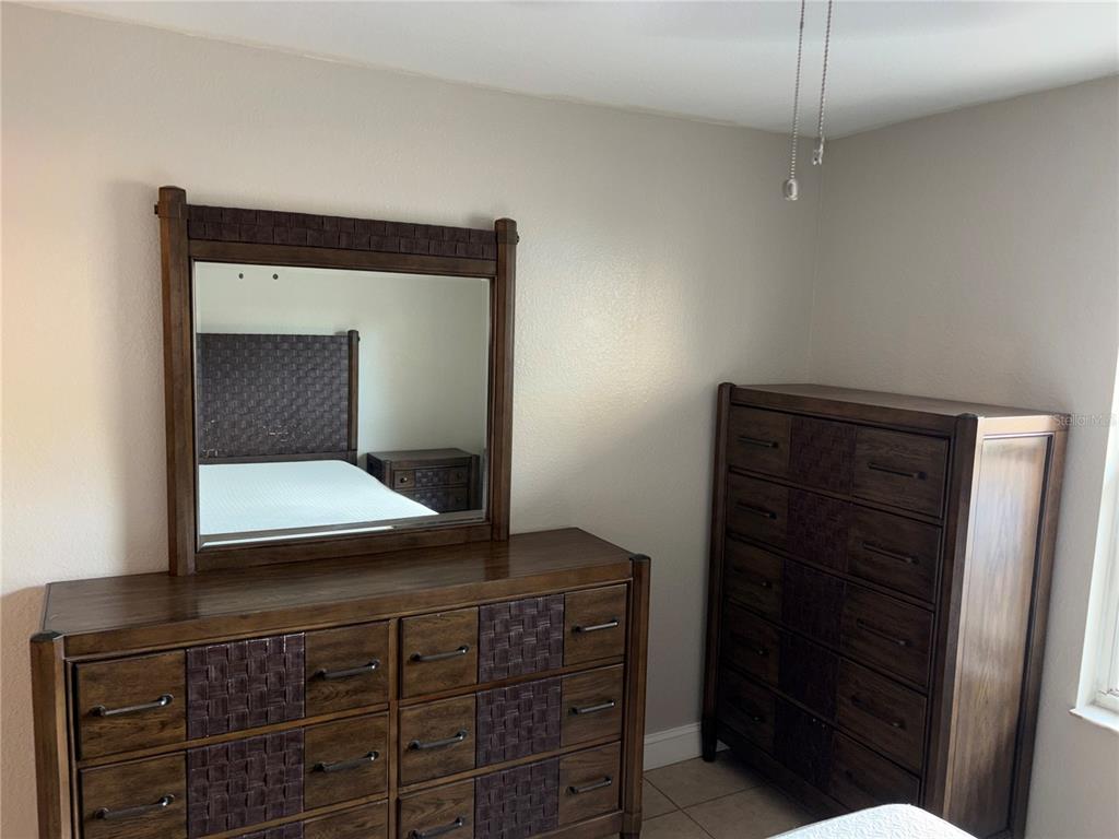 A bedroom features a wooden dresser with a mirror and a matching tall chest — 5822 CONGRESS STREET UNIT 104, NEW PORT RICHEY, FL
