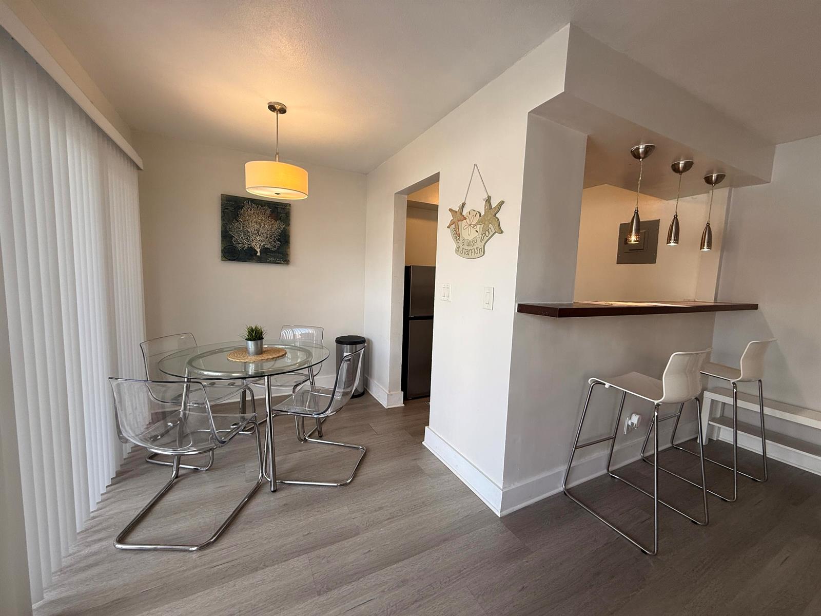 A dining area with a glass table and clear chairs next to a kitchen breakfast bar — 3226 NE 12th Street # 3, Pompano Beach FL 33062, POMPANO BEACH, FL