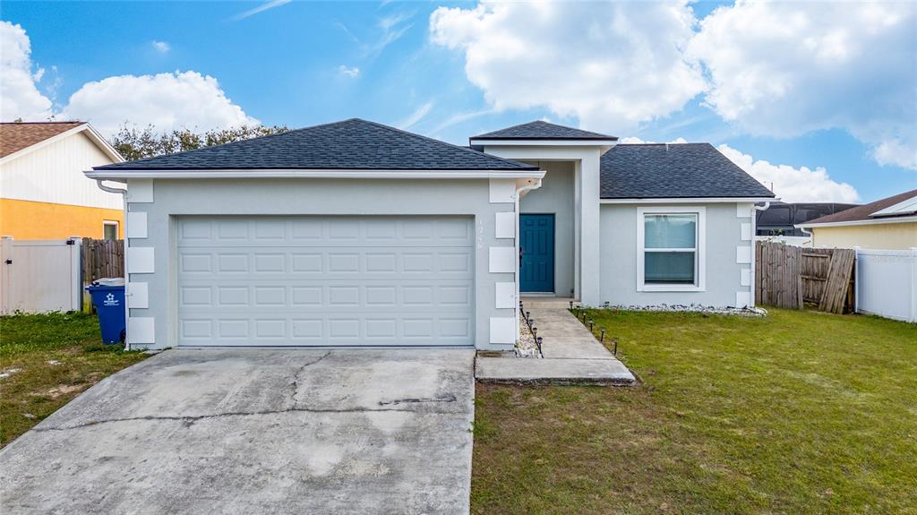 A single-story house features a two-car garage, a blue front door, and a concrete driveway — 1246 WESTWINDS DRIVE, DAVENPORT, FL