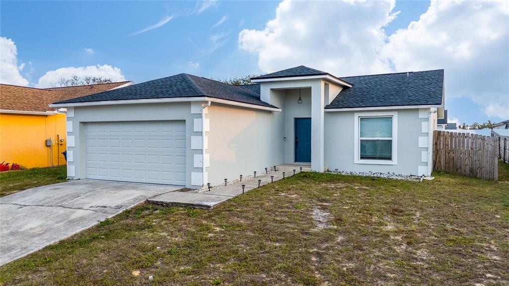 A single-story house with a gray exterior, a two-car garage, and a blue front door — 1246 WESTWINDS DRIVE, DAVENPORT, FL