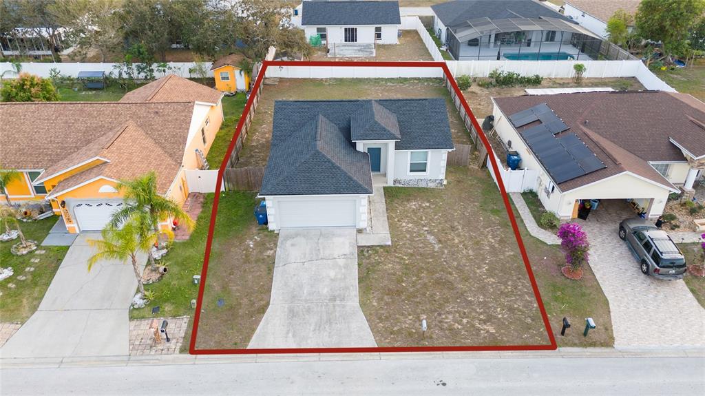An aerial view shows a single-story house with a dark roof and a concrete driveway — 1246 WESTWINDS DRIVE, DAVENPORT, FL