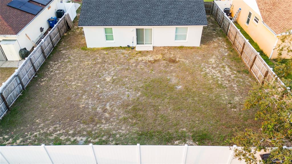 An aerial view shows a fenced backyard with sparse grass behind a single-story house — 1246 WESTWINDS DRIVE, DAVENPORT, FL