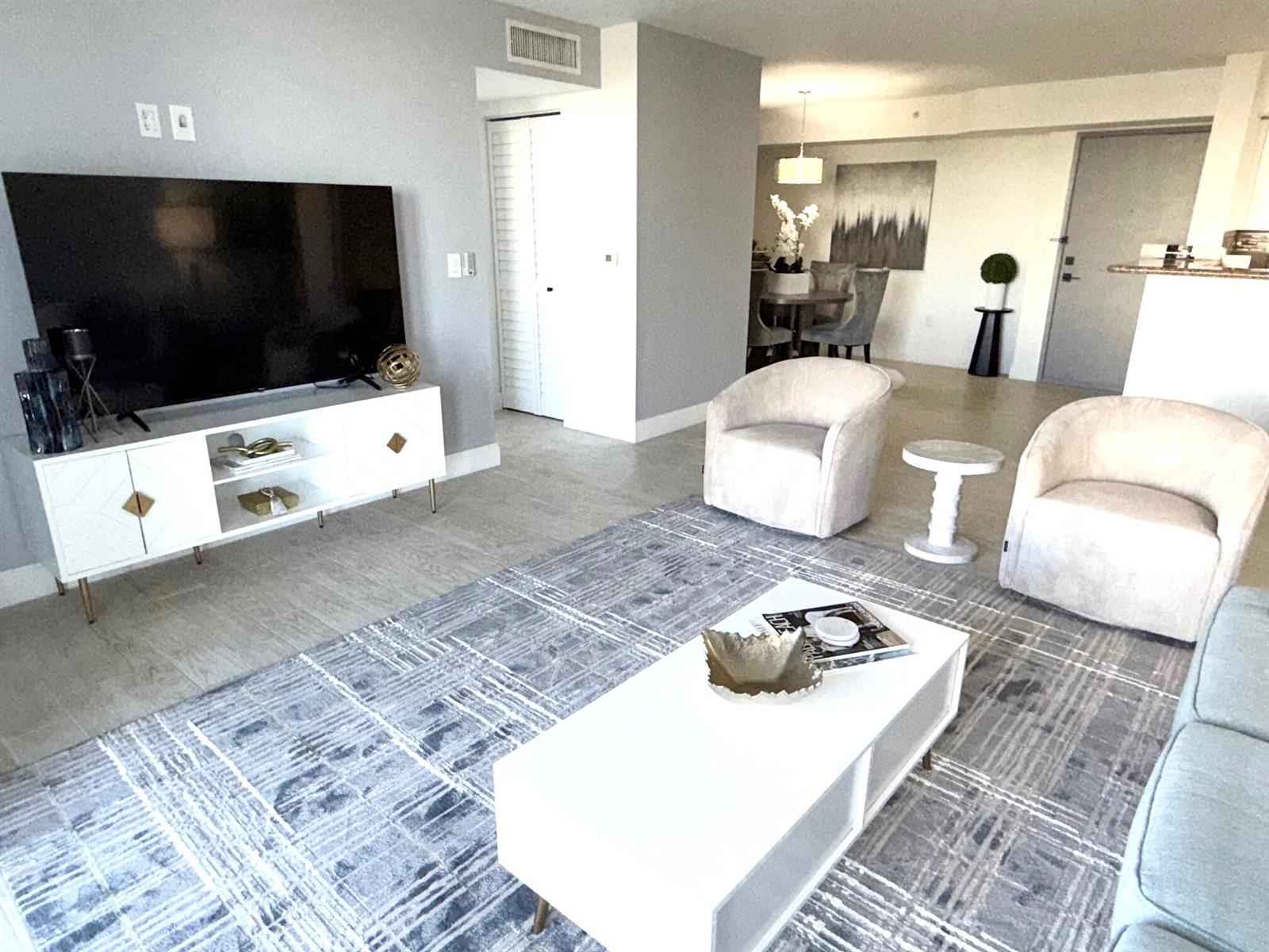 A living room features a white media console, two beige armchairs, and a patterned rug — 3594 S Ocean Boulevard # 406, Highland Beach FL 33487, HIGHLAND BEACH, FL