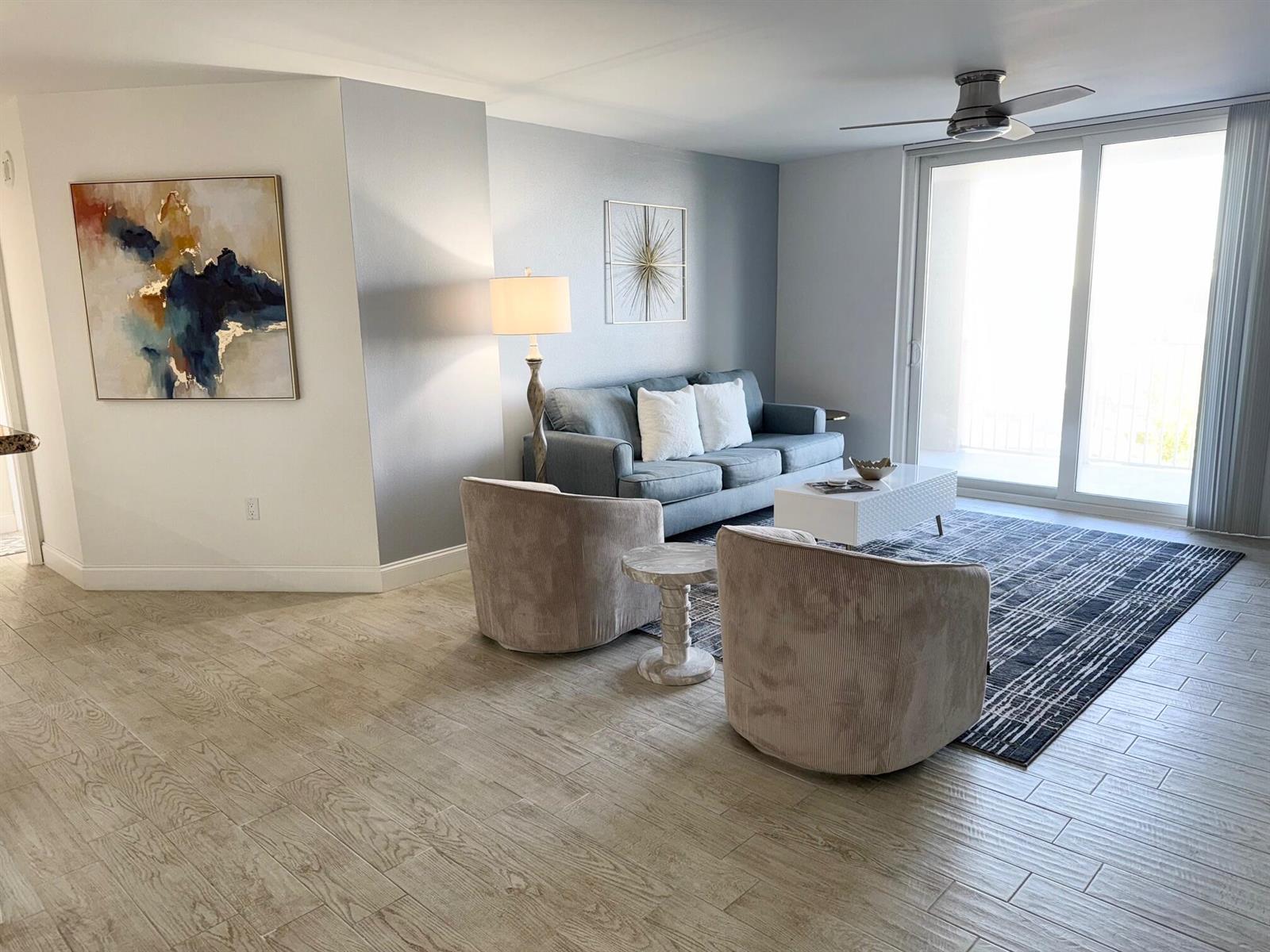 A living room features a blue sofa, two beige armchairs, and a patterned area rug — 3594 S Ocean Boulevard # 406, Highland Beach FL 33487, HIGHLAND BEACH, FL