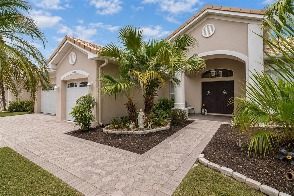 A beige house exterior features a paved driveway, a palm tree, and a front entryway — 3609 VALLEYVIEW DRIVE, KISSIMMEE, FL