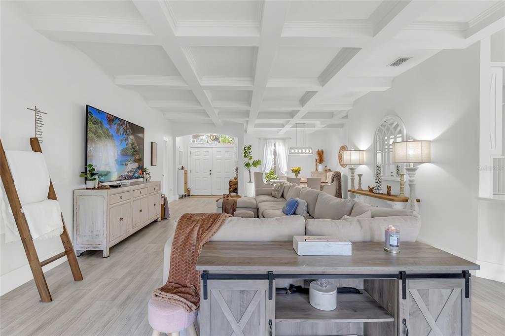 A bright living room features a coffered ceiling, light wood flooring, and a sectional sofa — 3609 VALLEYVIEW DRIVE, KISSIMMEE, FL