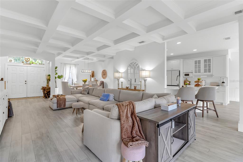 An open-concept living room and kitchen feature a coffered ceiling and light wood-look flooring — 3609 VALLEYVIEW DRIVE, KISSIMMEE, FL