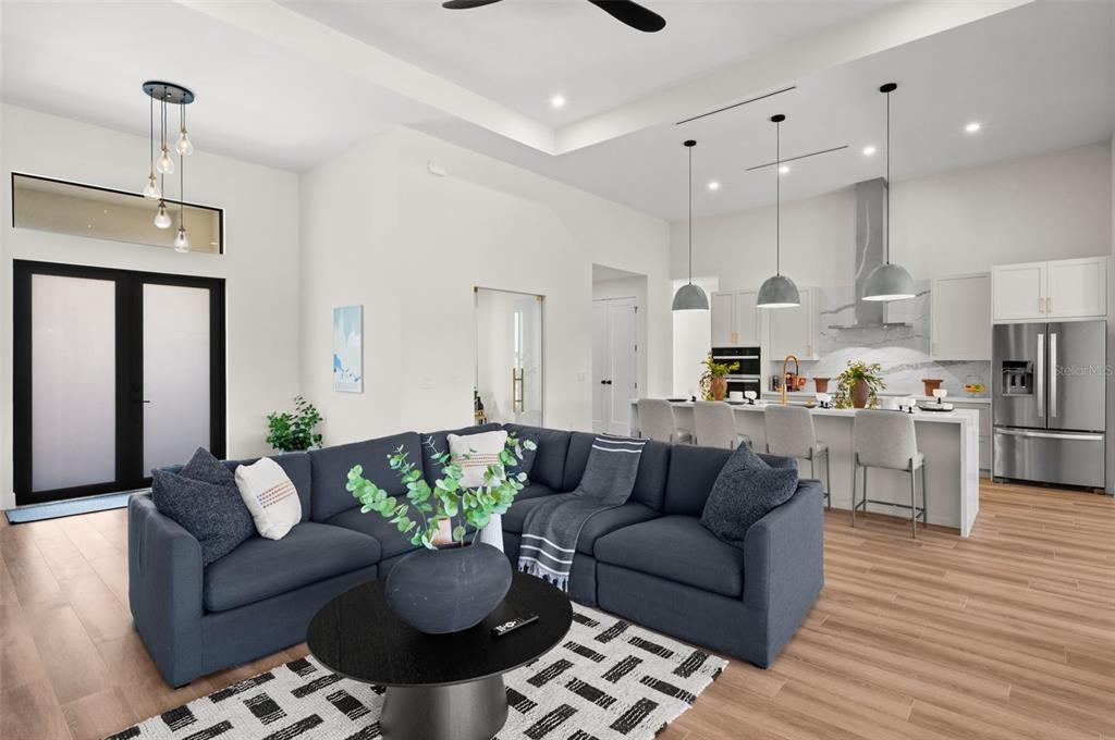 A modern open-concept living room and kitchen featuring a blue sectional sofa and island seating — 10522 RIVERSIDE ROAD, PORT CHARLOTTE, FL