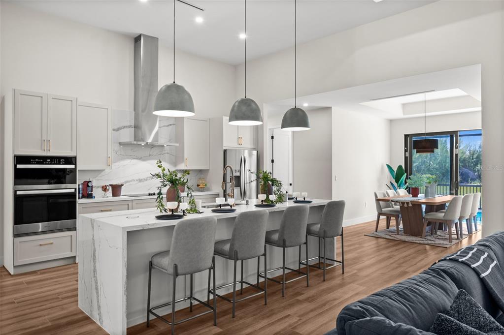 A modern kitchen features a large marble-topped island, gray bar stools, and stainless steel appliances — 10522 RIVERSIDE ROAD, PORT CHARLOTTE, FL