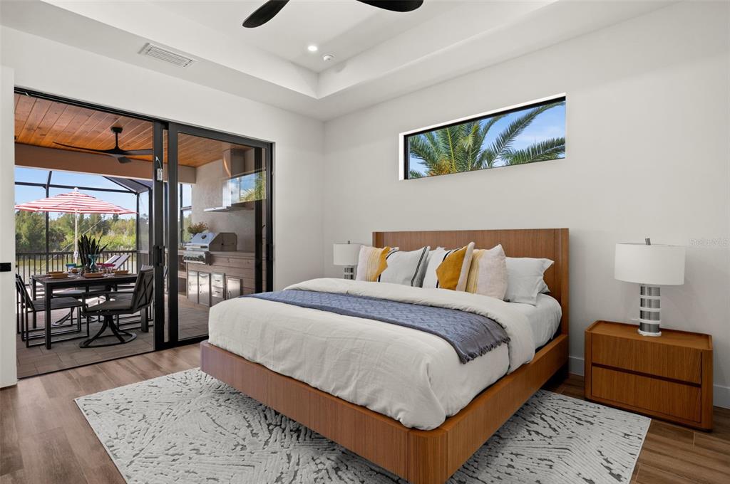 A modern bedroom features a wooden bed frame, a patterned rug, and sliding glass patio doors — 10522 RIVERSIDE ROAD, PORT CHARLOTTE, FL