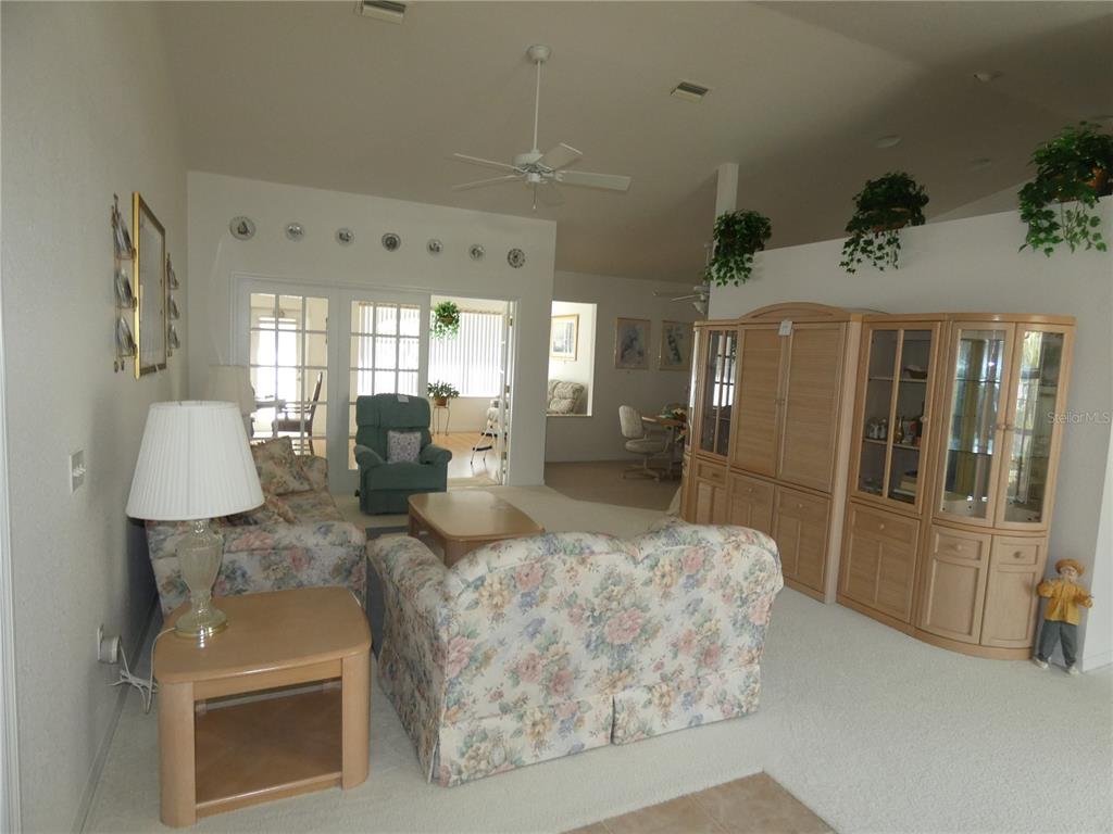 A living room features floral sofas, a light wood entertainment center, and white carpeting — 9610 SW 198TH CIRCLE, DUNNELLON, FL