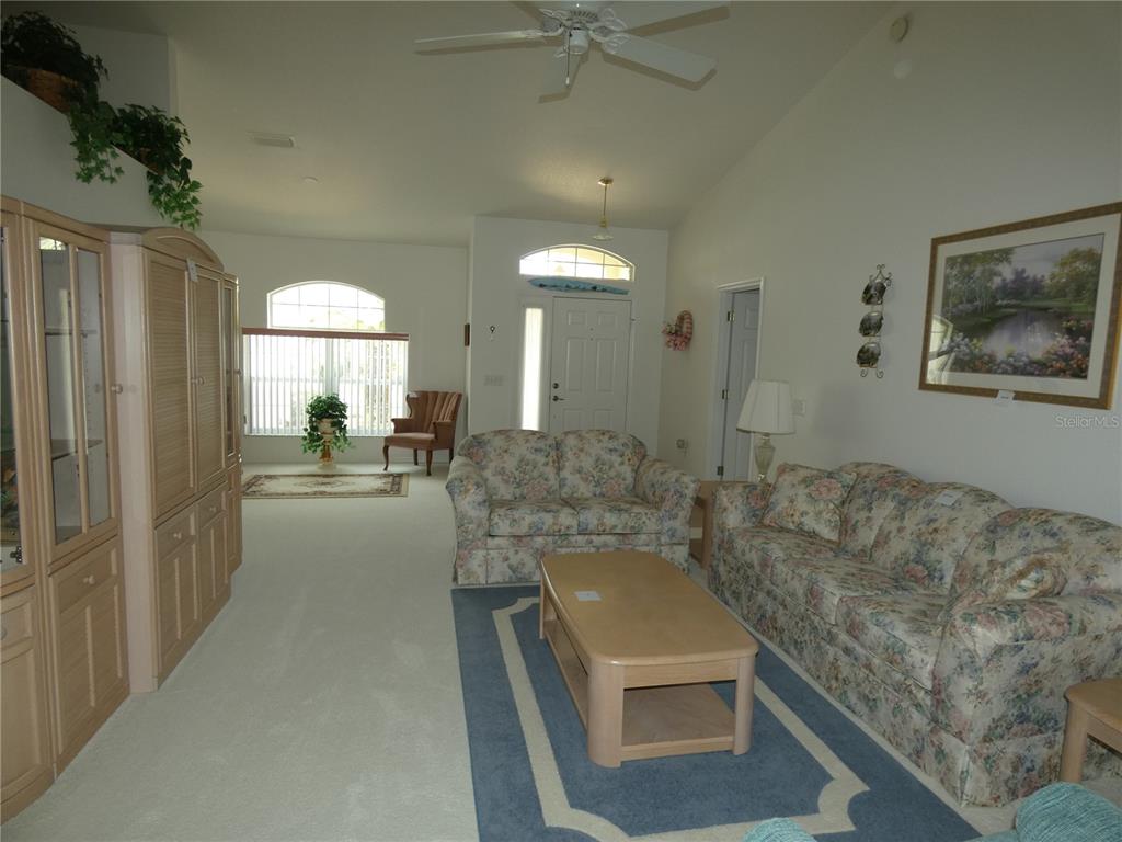 A living room features floral sofas, a coffee table, and a large entertainment center — 9610 SW 198TH CIRCLE, DUNNELLON, FL
