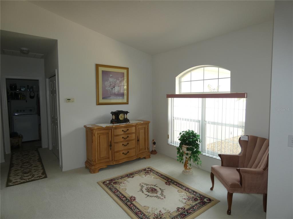 A carpeted room features a wooden sideboard, a patterned area rug, and a pink armchair — 9610 SW 198TH CIRCLE, DUNNELLON, FL