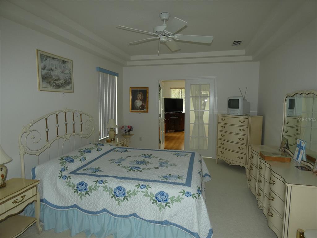 A bedroom features a white metal bed frame, floral bedding, a dresser, and a ceiling fan — 9610 SW 198TH CIRCLE, DUNNELLON, FL