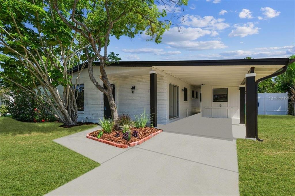 A single-story white house with a brick-bordered garden bed and a covered carport — 6551 S WEST SHORE CIRCLE, TAMPA, FL