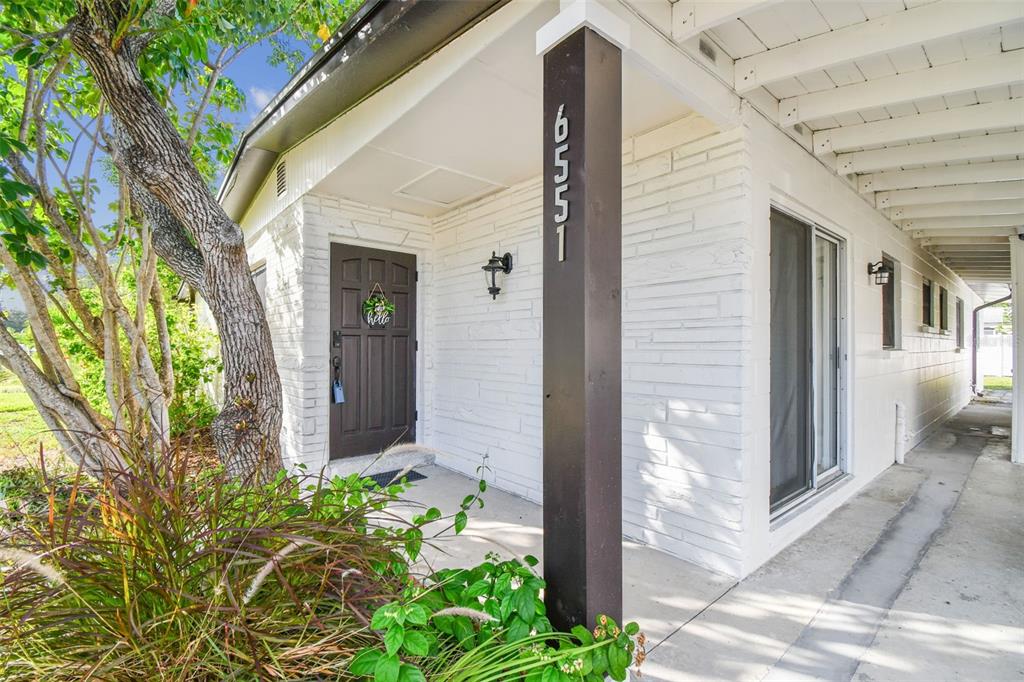 A white brick house exterior features a dark brown front door and a covered walkway — 6551 S WEST SHORE CIRCLE, TAMPA, FL