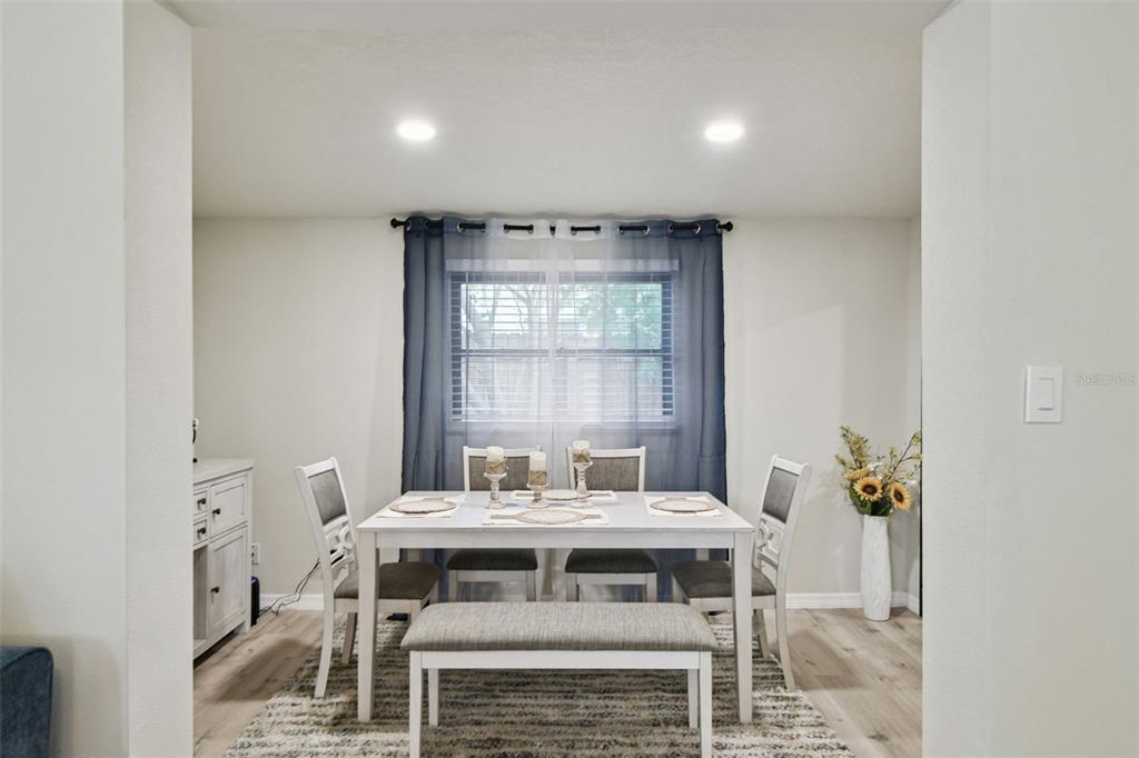 A dining room features a white table with chairs and a bench on a rug — 6551 S WEST SHORE CIRCLE, TAMPA, FL
