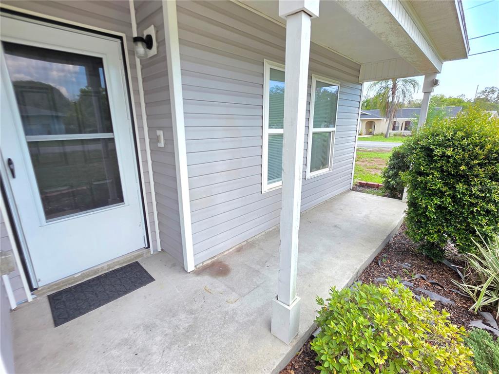 A concrete porch leads to a white front door on a house with gray siding — 6210 ALDERWOOD STREET, SPRING HILL, FL