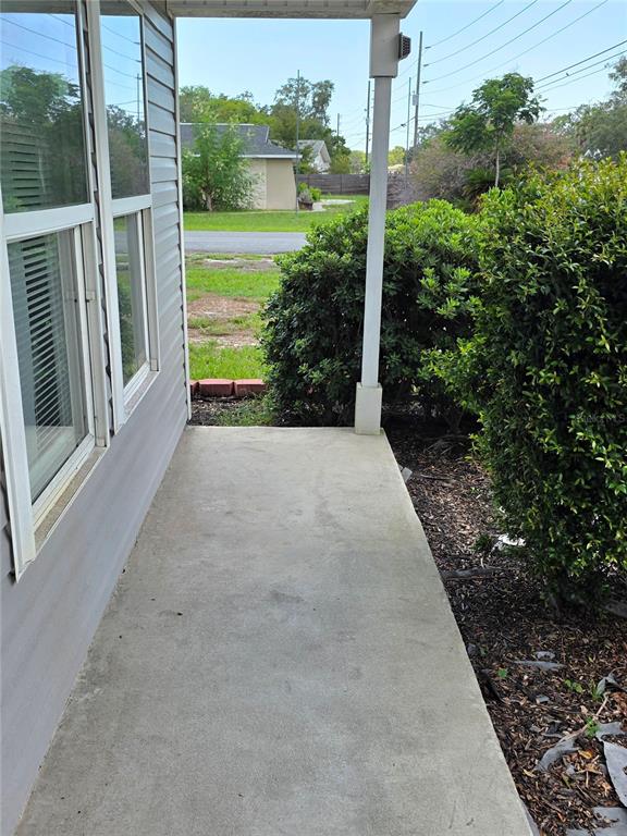 A concrete porch sits beside a house with white siding and a support pillar — 6210 ALDERWOOD STREET, SPRING HILL, FL