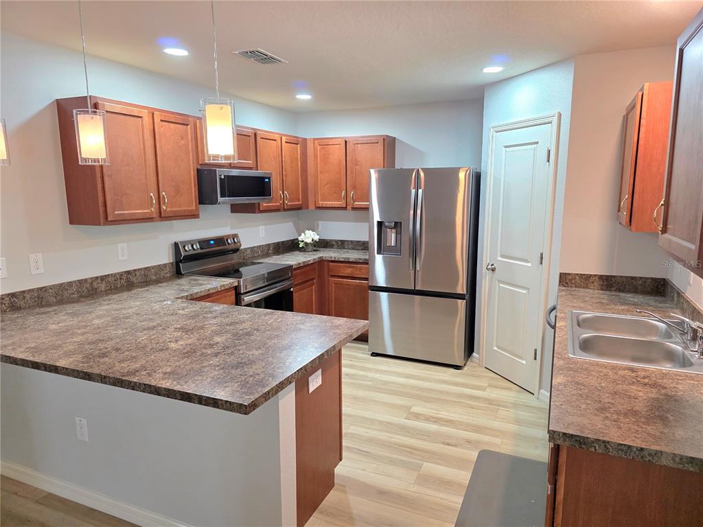A kitchen features wood cabinets, stainless steel appliances, and dark laminate countertops — 6210 ALDERWOOD STREET, SPRING HILL, FL