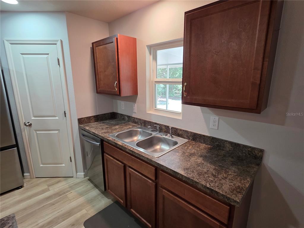 A kitchen features wood cabinets, a double-basin sink, laminate countertops, and light-colored flooring — 6210 ALDERWOOD STREET, SPRING HILL, FL