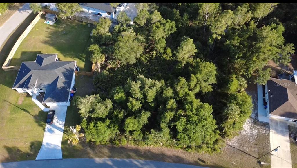 An aerial view shows a wooded vacant lot situated between two residential houses — PETAL ROAD, NORTH PORT, FL