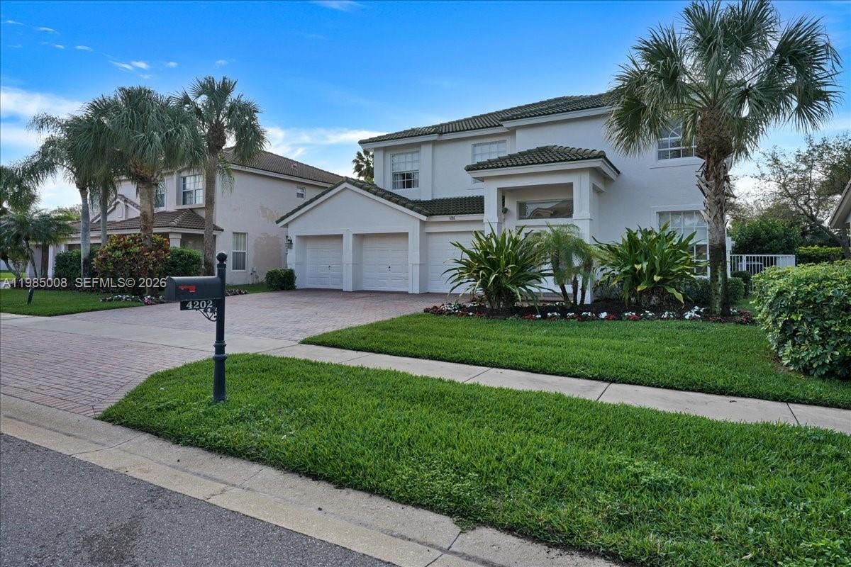 A two-story suburban house with a three-car garage and palm trees in the front yard — 4202 Bahia Isle Cir, Wellington FL 33449, WELLINGTON, FL