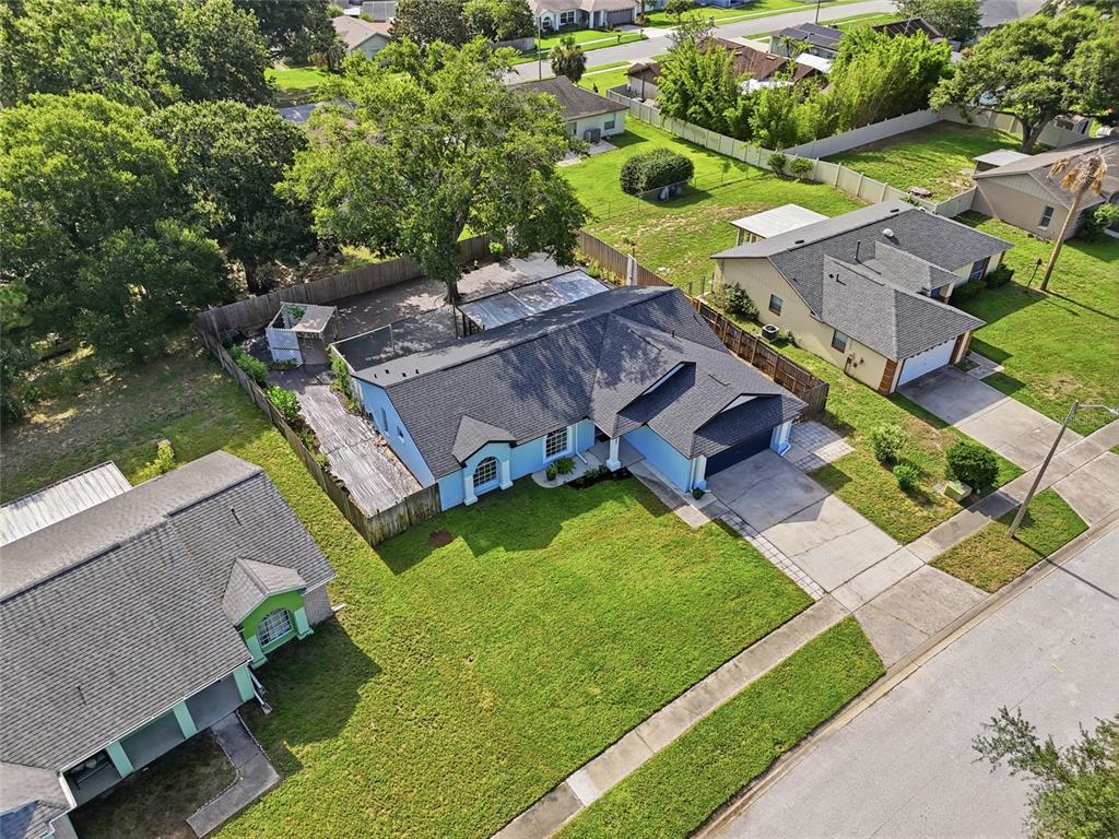 An aerial view shows a blue house with a dark roof, driveway, and fenced backyard — 15617 KENSINGTON TRAIL, CLERMONT, FL