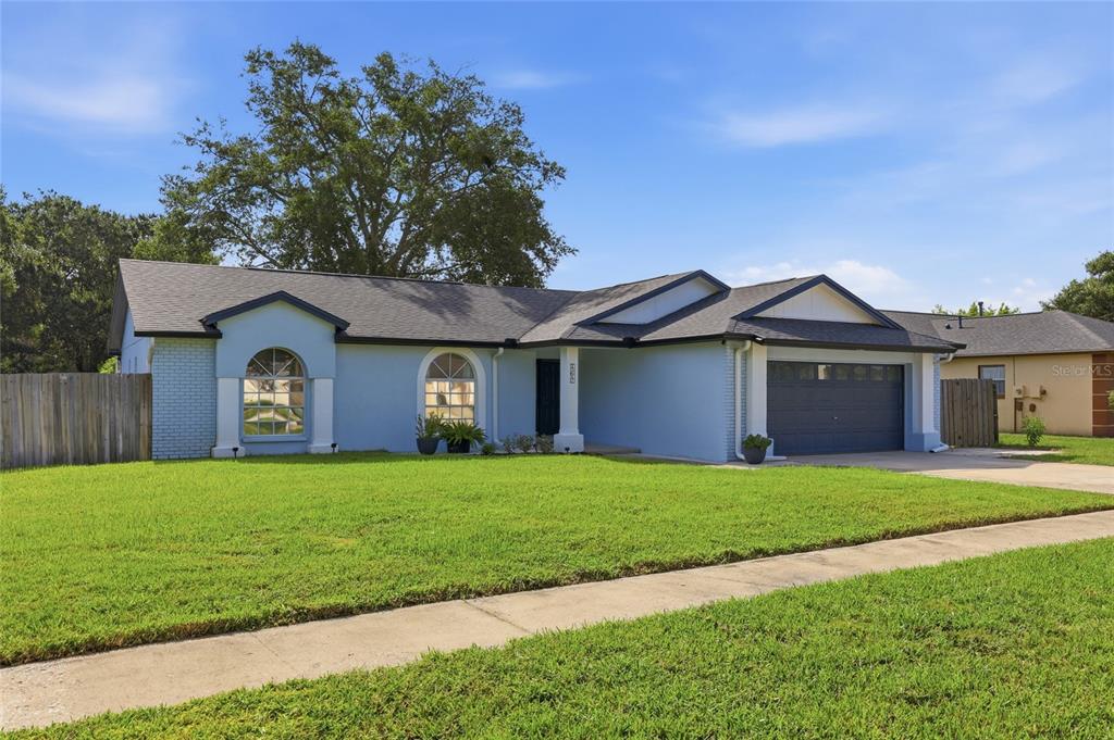 A light blue single-story house with a dark roof and a two-car garage — 15617 KENSINGTON TRAIL, CLERMONT, FL