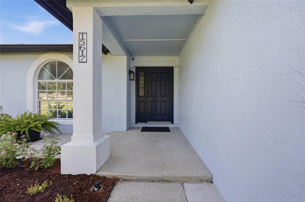A light blue house features a covered entryway with a dark door and address numbers — 15617 KENSINGTON TRAIL, CLERMONT, FL