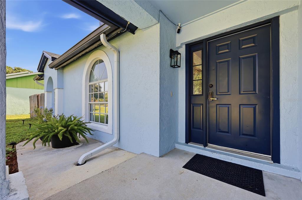 A light blue house exterior features a dark blue front door and an arched window — 15617 KENSINGTON TRAIL, CLERMONT, FL