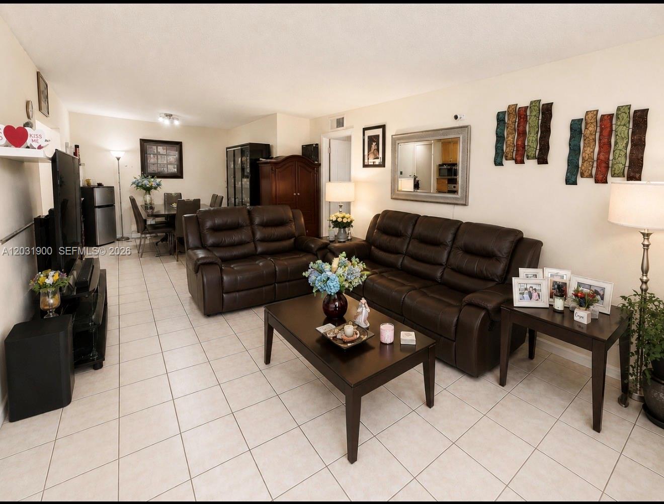 An exterior view of a ground-floor apartment entrance with a patio, chairs, and security door — 12860 SW 43rd Dr # B, Miami FL 33175, MIAMI, FL