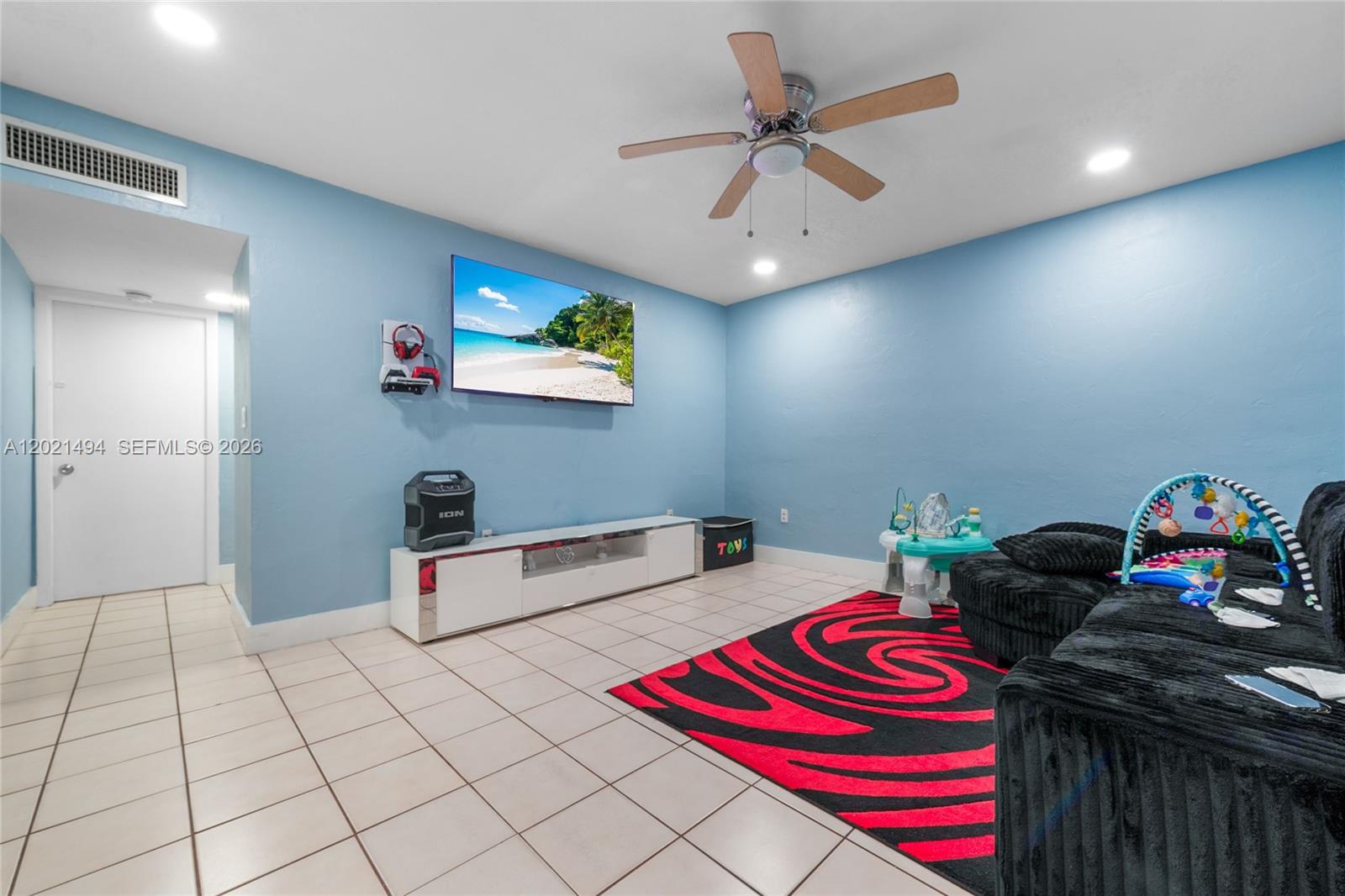 A room with blue walls, tile flooring, a ceiling fan, and a wall-mounted television — 4655 Palm Ave # 332, Hialeah FL 33012, HIALEAH, FL
