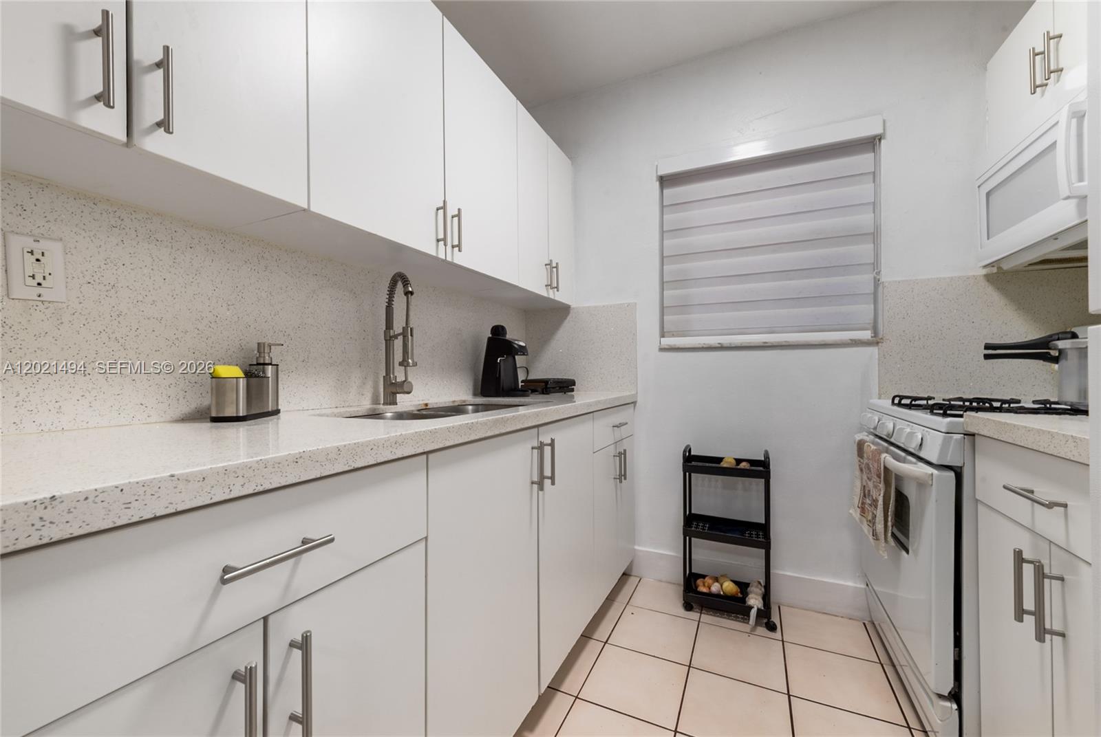 A galley kitchen features white cabinets, light countertops, a stainless steel sink, and white appliances — 4655 Palm Ave # 332, Hialeah FL 33012, HIALEAH, FL