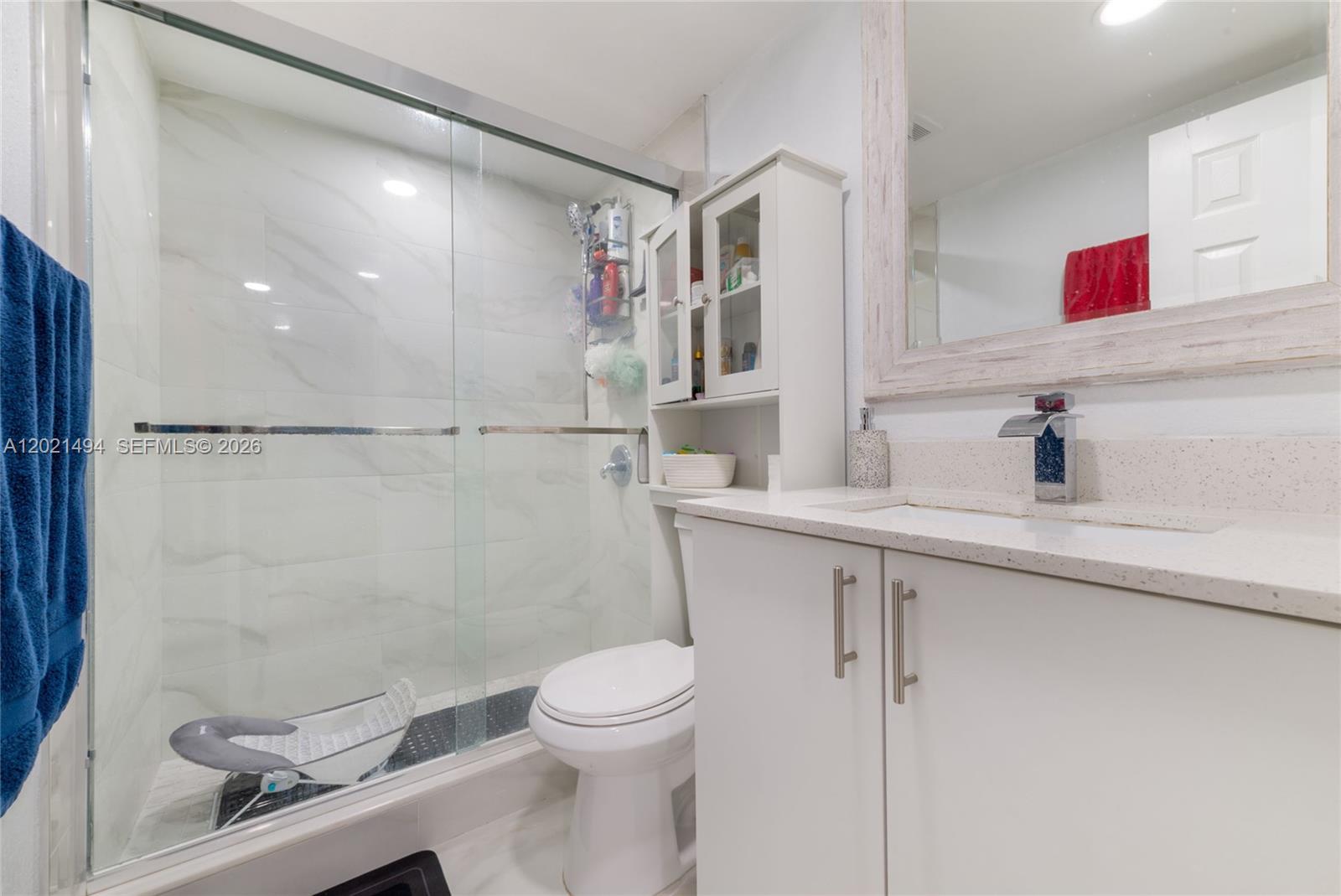 A bathroom features a glass-enclosed shower, a white vanity with a stone countertop, and a toilet — 4655 Palm Ave # 332, Hialeah FL 33012, HIALEAH, FL