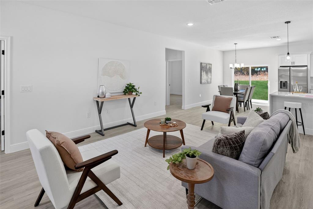 A living room with light wood floors, a grey sofa, and an open kitchen area — 1243 W SHADY LANE, CITRUS SPRINGS, FL