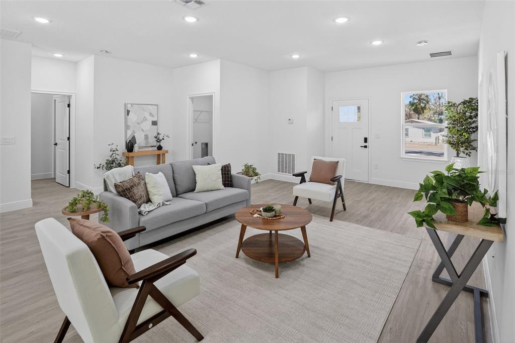 A bright living room features light wood-look flooring, a gray sofa, and two accent chairs — 1243 W SHADY LANE, CITRUS SPRINGS, FL
