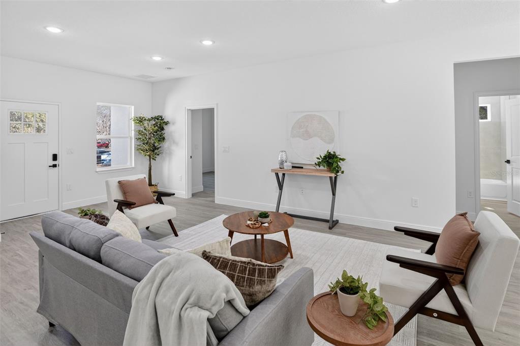 A living room features light gray flooring, white walls, a gray sofa, and two armchairs — 1243 W SHADY LANE, CITRUS SPRINGS, FL