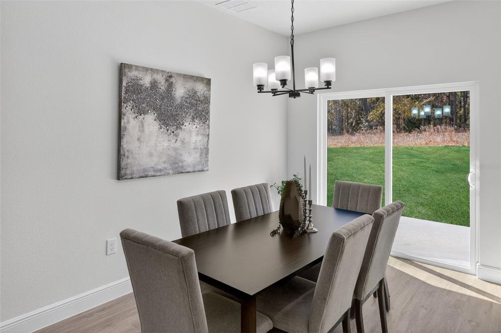 A dining room with a dark wood table, six grey chairs, and a sliding glass door — 1243 W SHADY LANE, CITRUS SPRINGS, FL