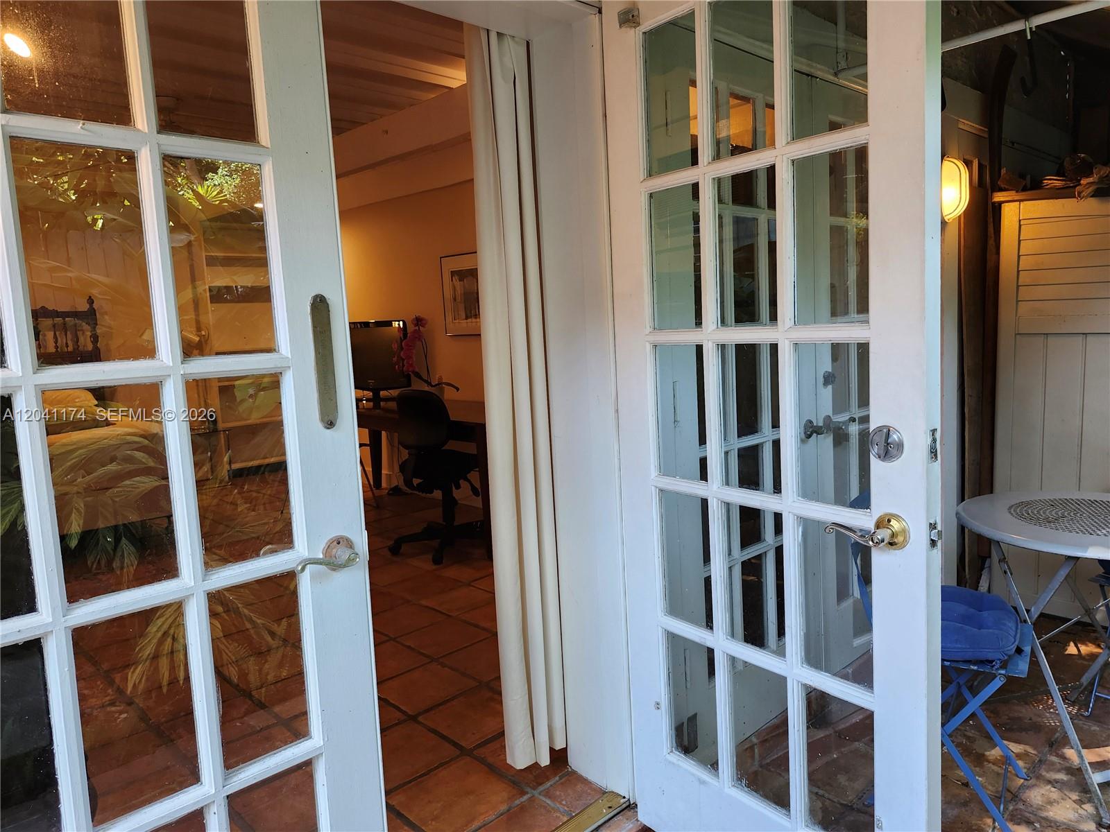 A patio features a small metal table and two chairs in front of French doors — 3940 Main, Miami FL 33133, MIAMI, FL
