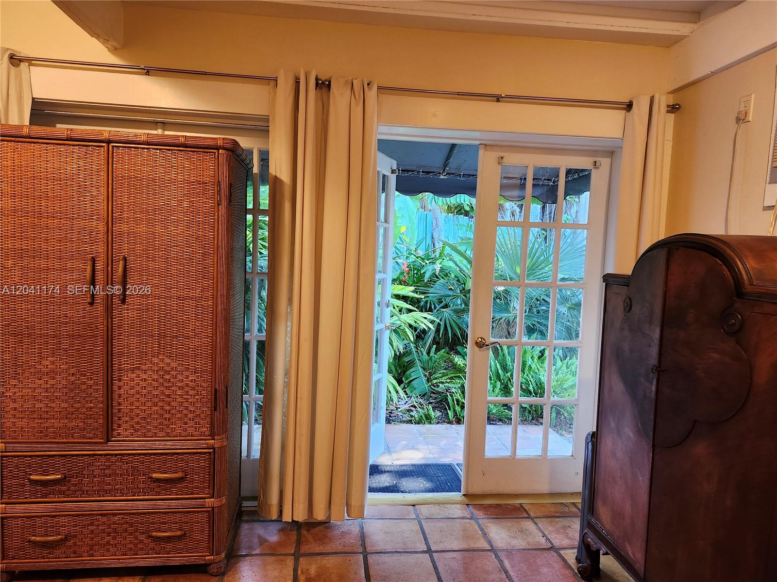A small wooden table and two chairs sit before glass doors overlooking a garden — 3940 Main, Miami FL 33133, MIAMI, FL