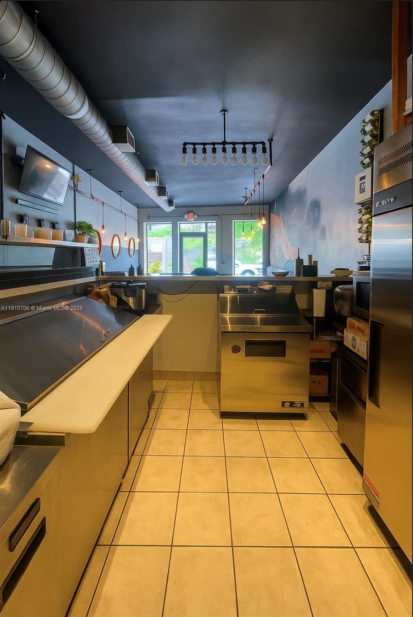 A commercial kitchen space with stainless steel equipment, tiled floors, and exposed industrial ceiling ductwork — 205 NE 35th St, Miami FL 33137, MIAMI, FL