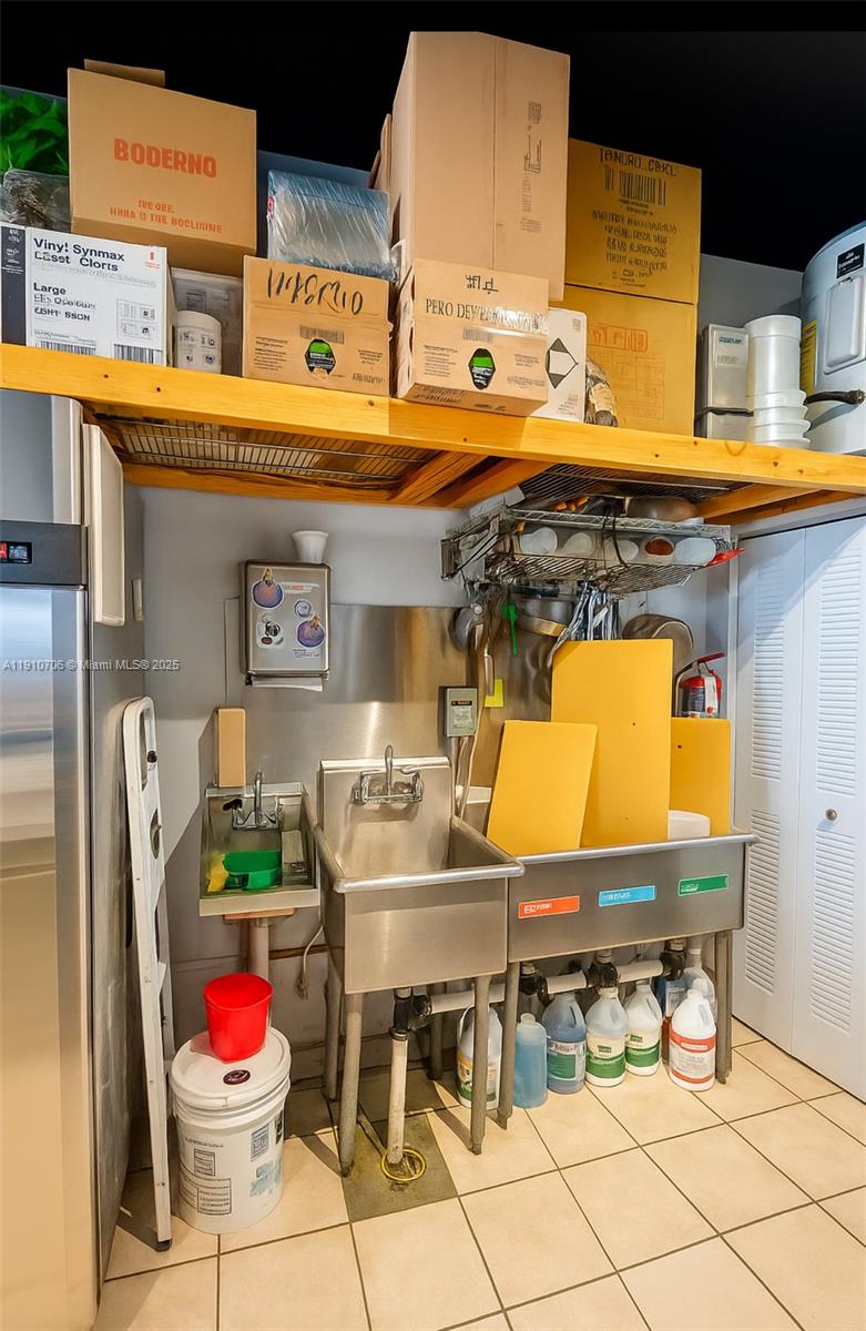 A commercial kitchen area features a stainless steel three-compartment sink and overhead storage shelving — 205 NE 35th St, Miami FL 33137, MIAMI, FL